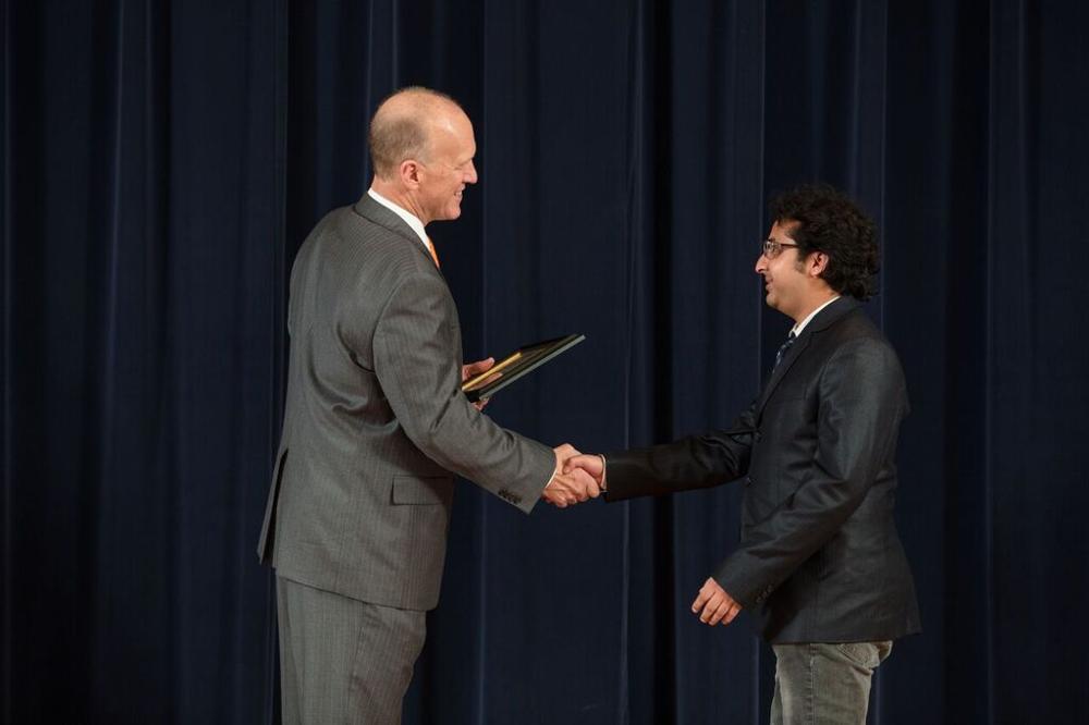 Doctor Potteiger shaking hands with an award recipient in a black jacket